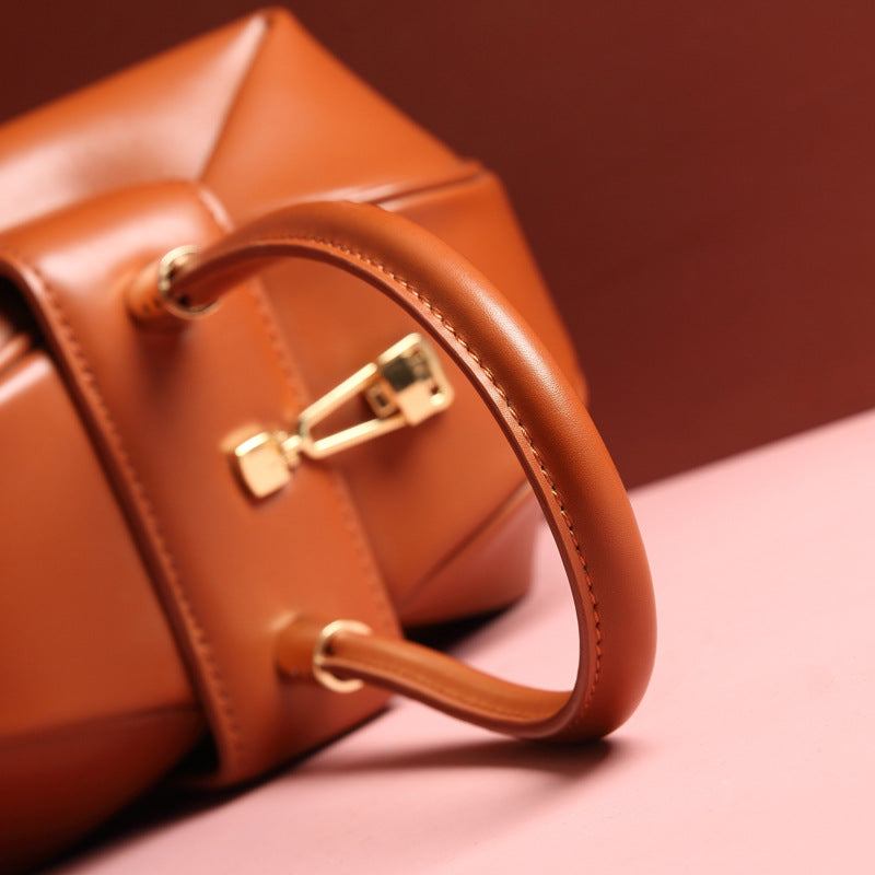 Cowhide Dumpling Tote Bag in orange leather with a curved single handle and gold-tone buckle closure