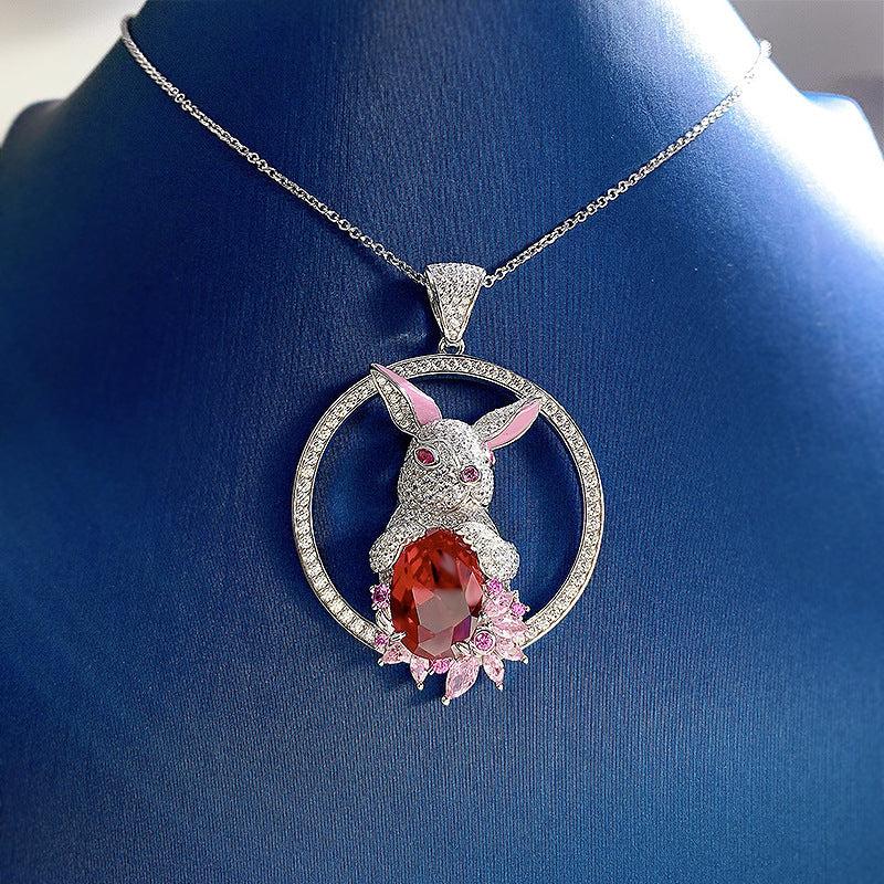 Rabbit Pendant Necklace with silver-tone rabbit, faceted deep red stone, crystal circle and pink floral accents