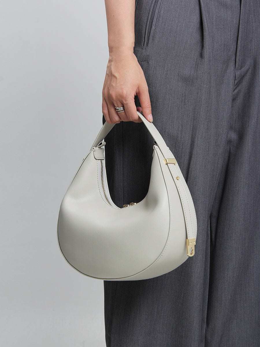 Cowhide Crossbody Bag in pale grey-white leather with a curved shape, zip closure and jointed strap