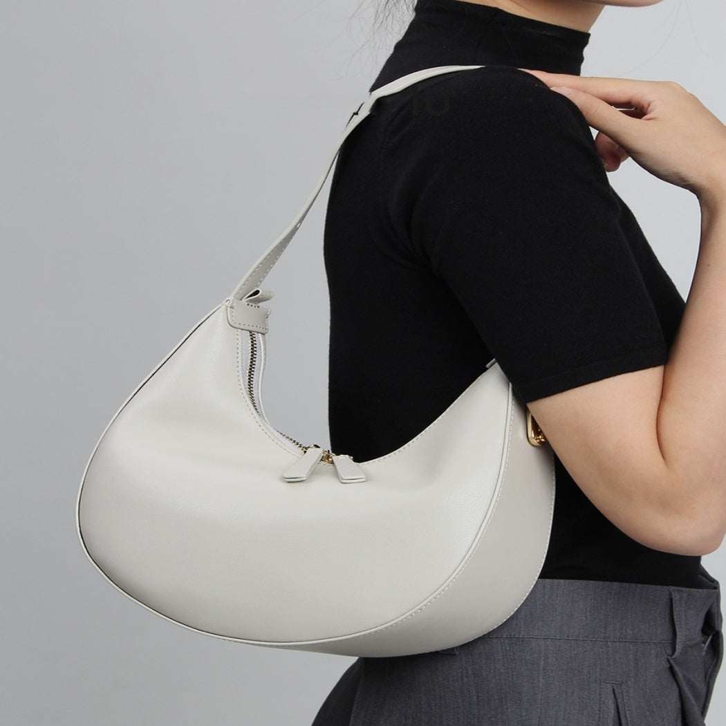 Cowhide Crossbody Bag in pale grey-white leather with a smooth curved body, zip closure and narrow strap
