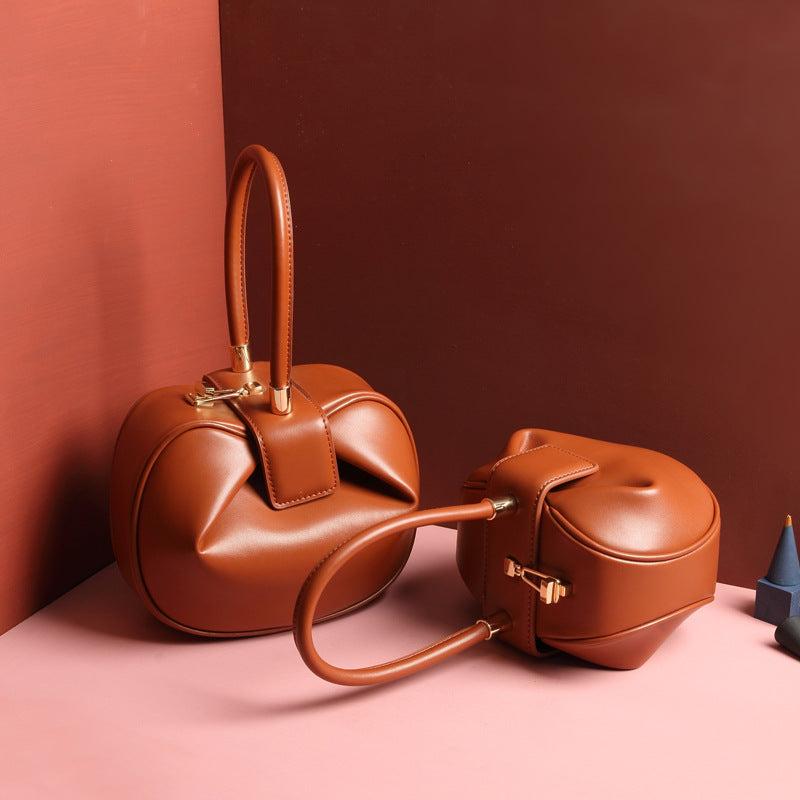 Cowhide Dumpling Tote Bag in brown leather with a curved slouchy shape, buckle closure and single handle