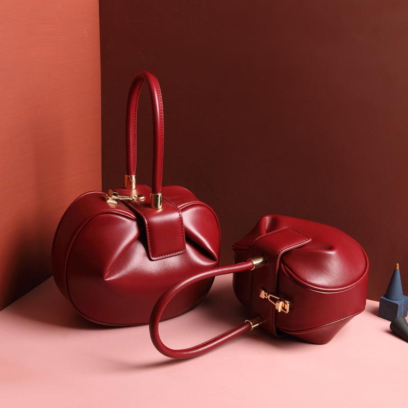 Cowhide Dumpling Tote Bag in deep red leather with rounded dumpling shape, single handle and buckle closure