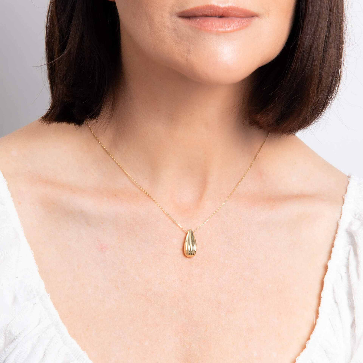 Elements Gold ridged teardrop necklace in polished yellow gold with a slim chain and textured pendant