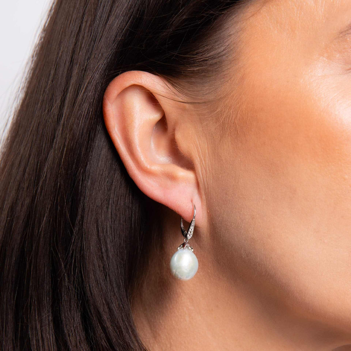 Elements Gold white gold drop earring with a lustrous baroque pearl and small sparkling topaz detail