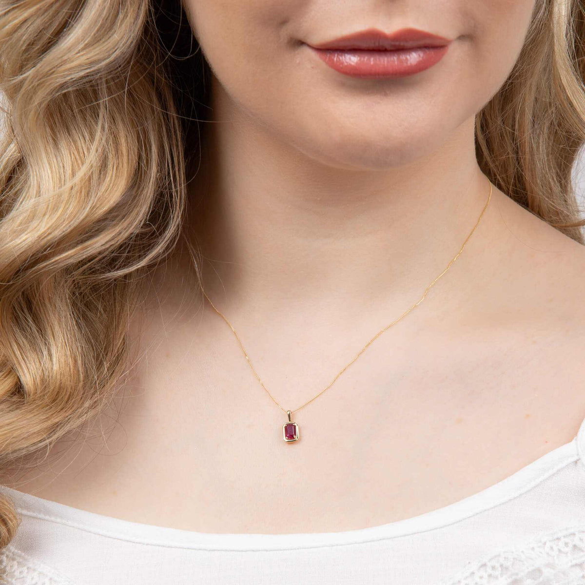 Elements Gold pendant in polished yellow gold with a small red octagonal gemstone and delicate chain