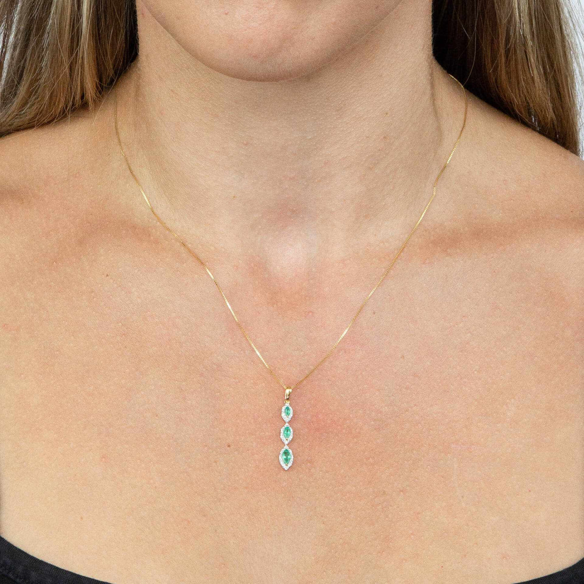 Marquise pendant in yellow gold with three green emeralds and diamond halos in a slim vertical design