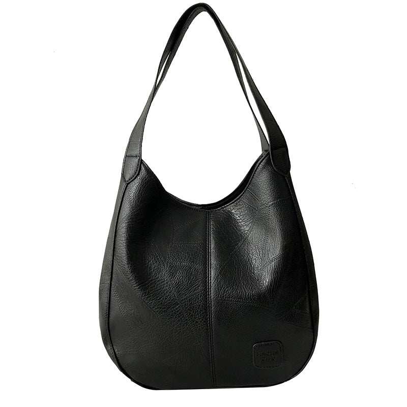 Vegan Leather Tote Bag in black with soft textured finish, curved shape, long shoulder straps and front logo patch