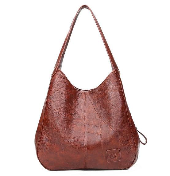 Vegan Leather Tote Bag in brown textured material with a soft slouchy shape, long shoulder strap and front logo patch